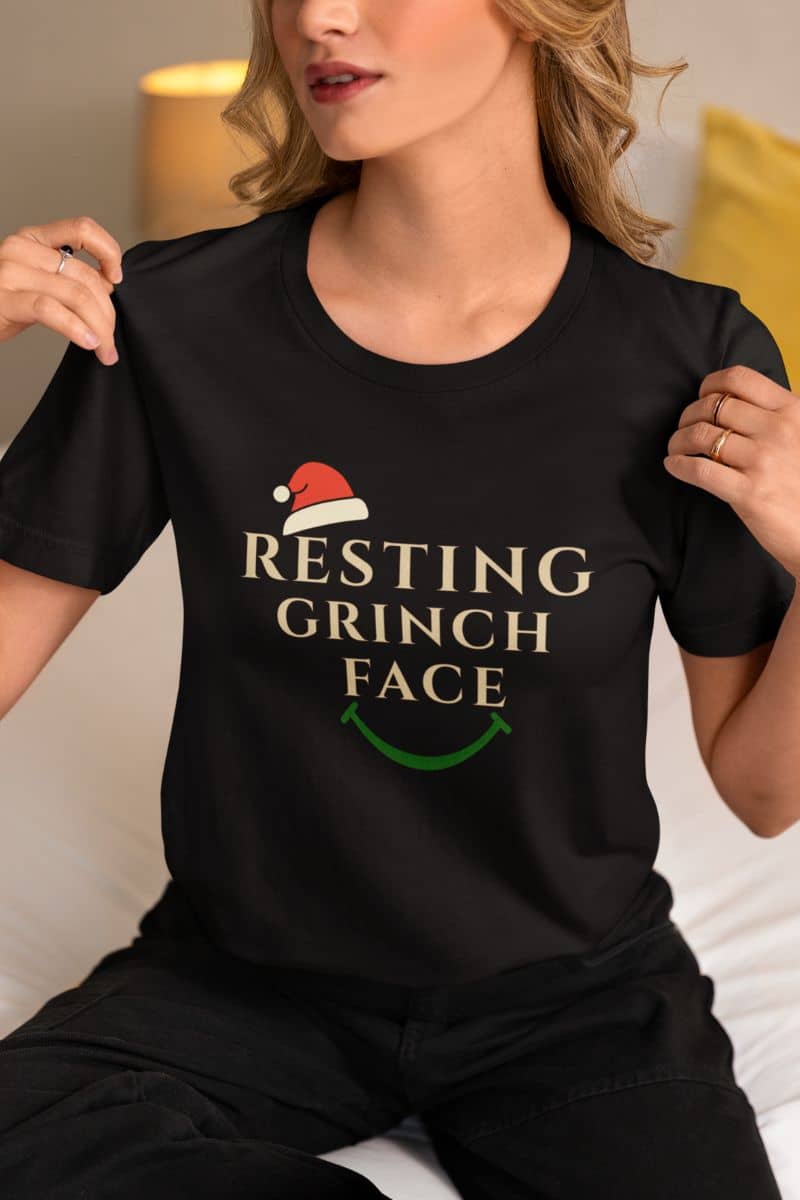 Anti social Xmas top with a person wearing a black t-shirt with 'Resting Grinch Face' text and graphic.