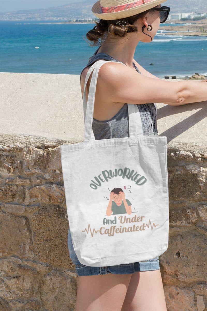 Caffeine addict tote bag with a girl carrying a tote bag and looking at the beach