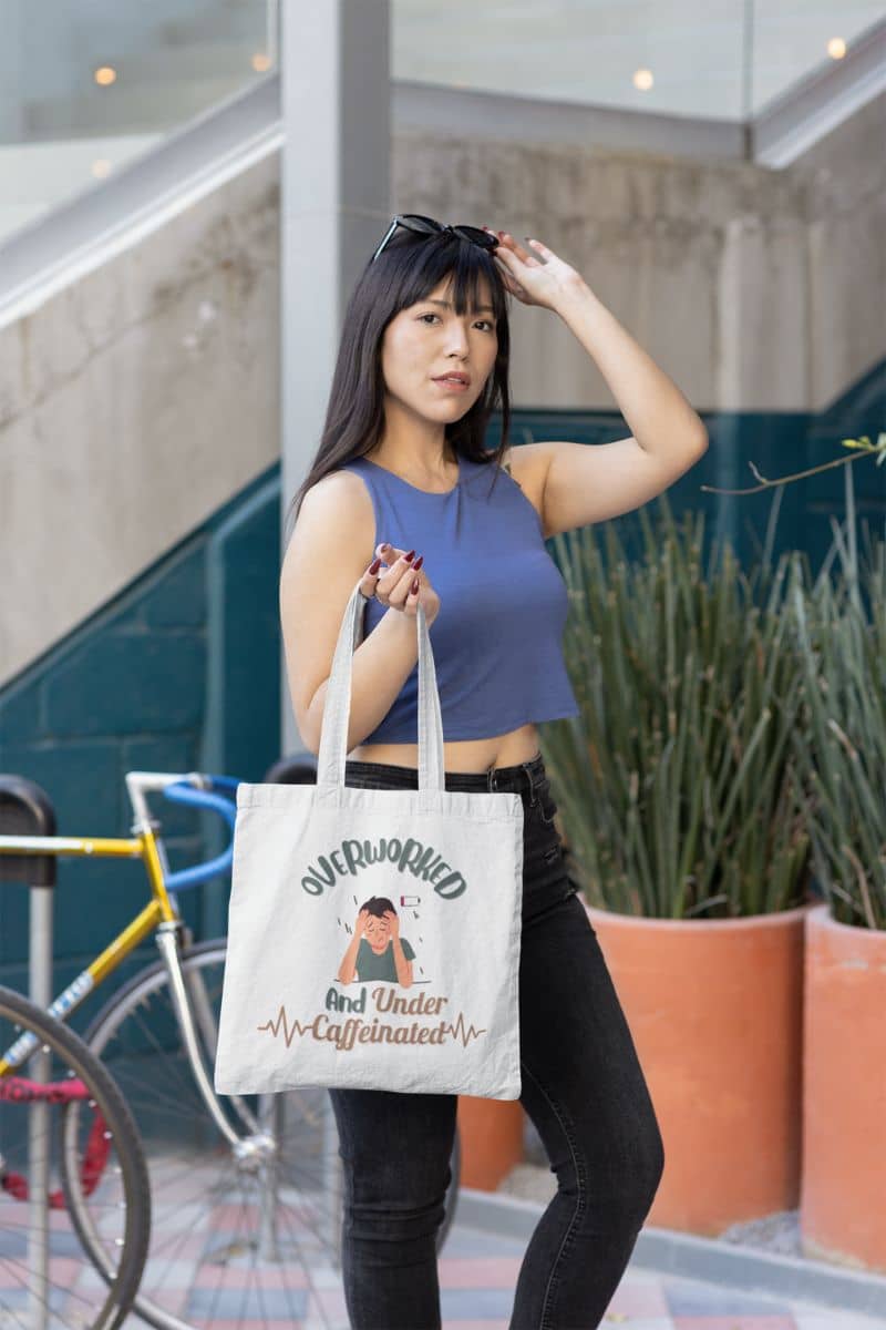 Caffeine addict tote bag with an asian girl posing with a tote bag and glasses on her head