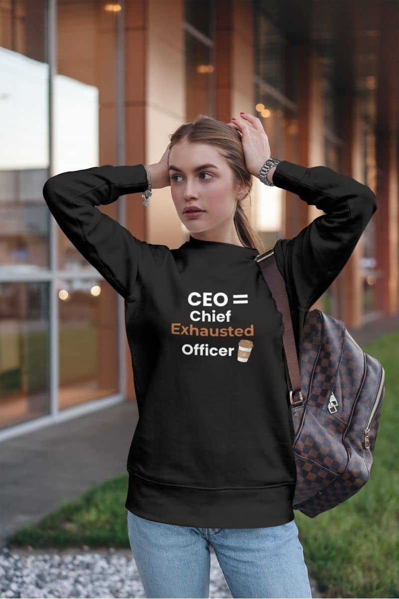 Chief exhausted officer pullover with a person wearing a black sweatshirt with a humorous quote 'CEO = Chief Exhausted Officer' outdoors.