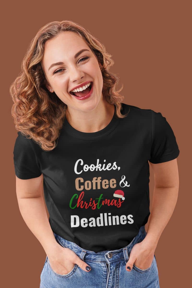 Christmas coffee shirt for work with a woman wearing a black t-shirt with 'Cookies, Coffee & Christmas Deadlines' text on a brown background