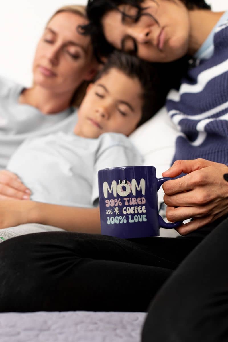 Coffee mug for moms with 2 women lying in bed with a boy while still holding a cup of coffee