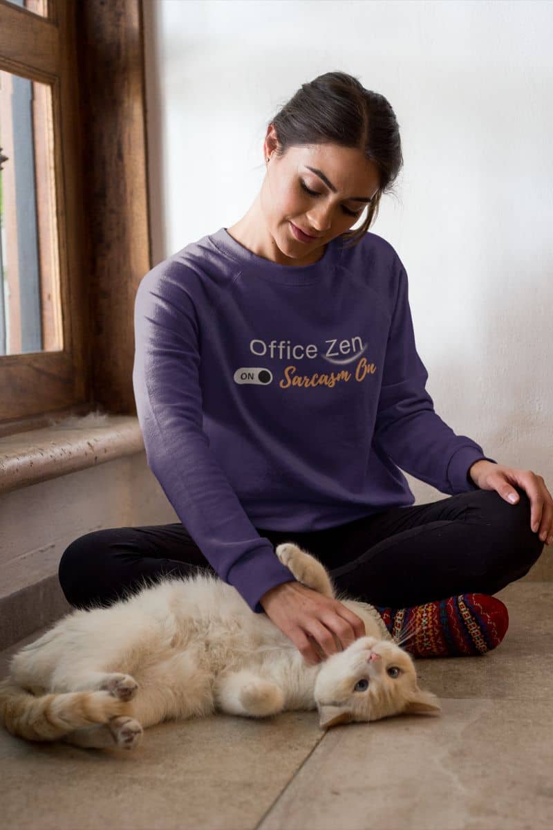 Comfortable oversized sweatshirt with a woman in a purple sweatshirt petting a cat on the floor near a window.