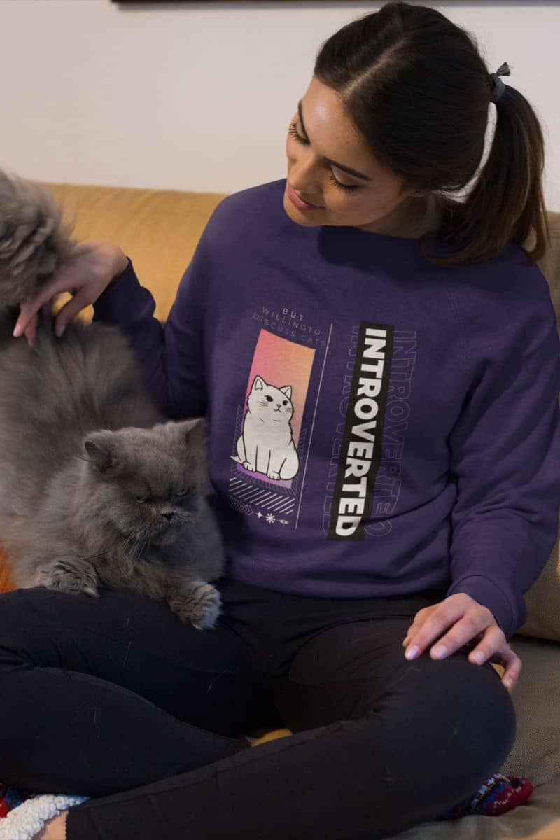Comfy introverted sweatshirt with a girl playing with her cat on the sofa