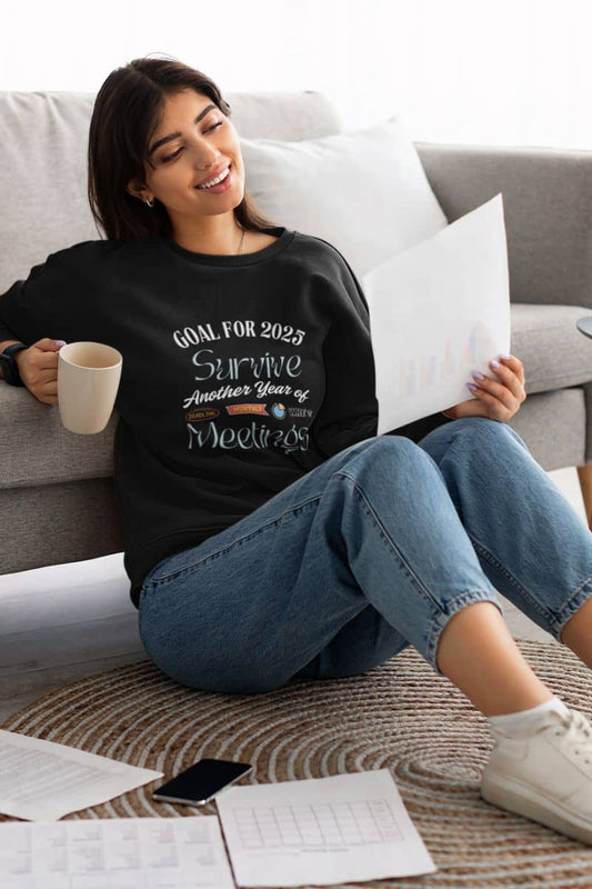 Comfy work sweatshirt with a girl sitting on the floor, leaning against the sofa with a report in one hand and a glass of water in the other