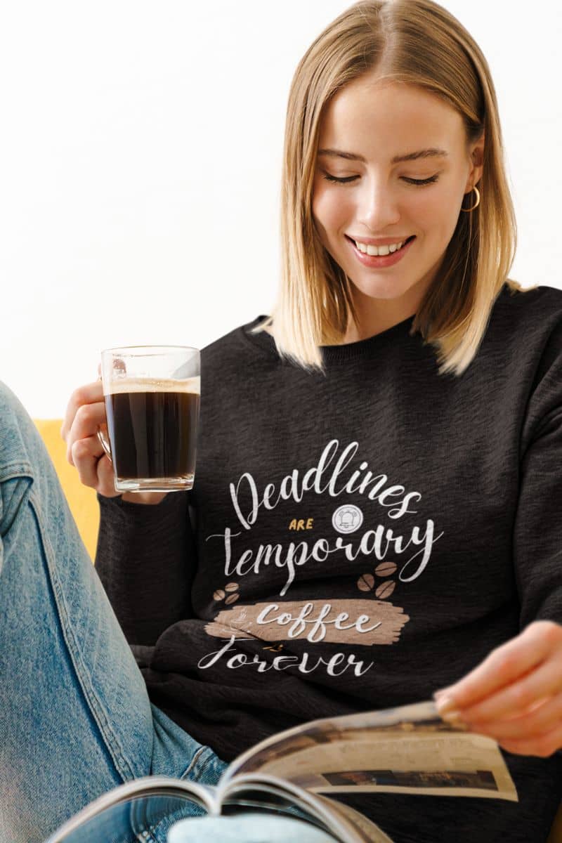 Cozy coffee enthusiast sweatshirt with a girl smiling while reading a book while holding a cup of coffee in her hand