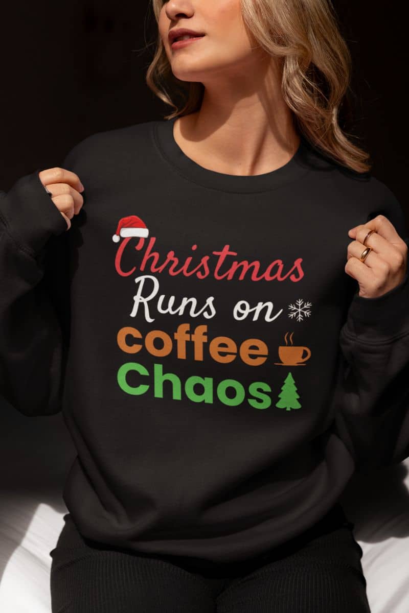 Cozy holiday sweatshirt with a person wearing a black sweatshirt with text 'Christmas Runs on Coffee & Chaos' on a dark background