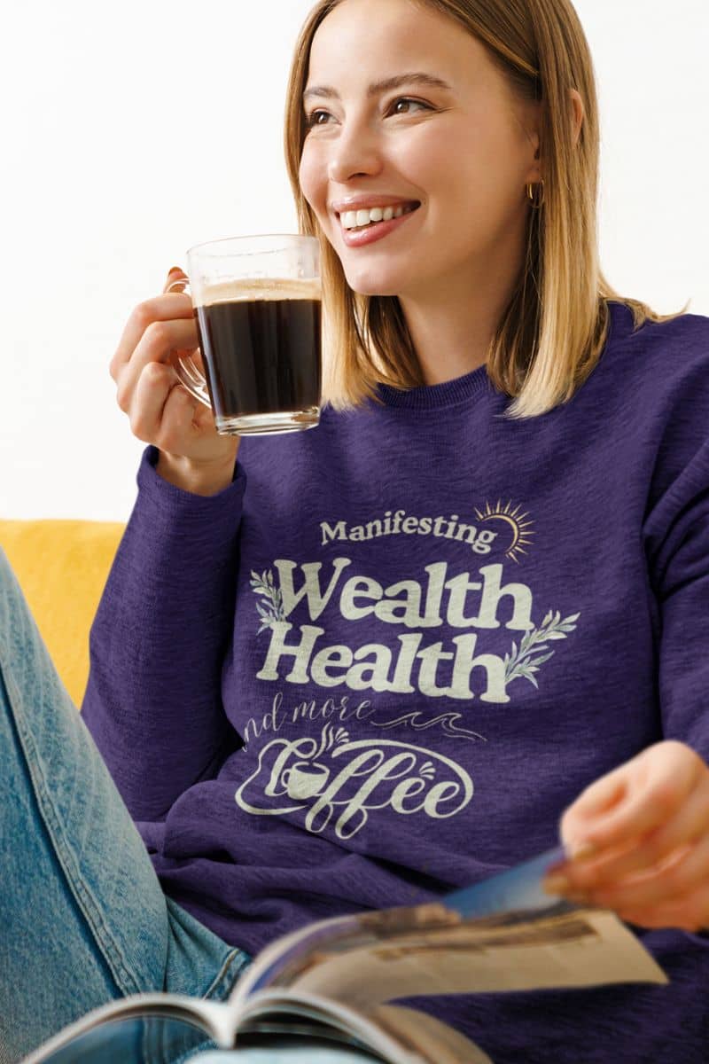 Cozy manifestation sweatshirt with a beautiful girl sitting on the sofa drinking coffee and reading a book