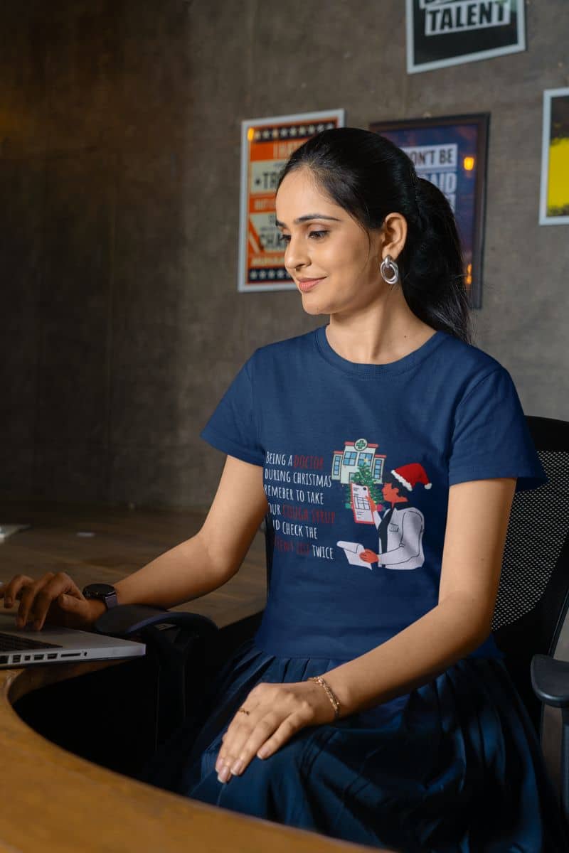 Doctor's Christmas Checklist T-Shirt with a girl sitting working on a laptop