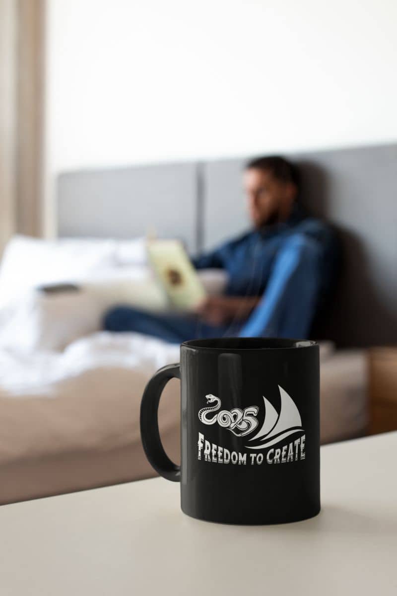 Freedom to create 11oz Mug with a man reading a book in bed while his coffee cup is on the table