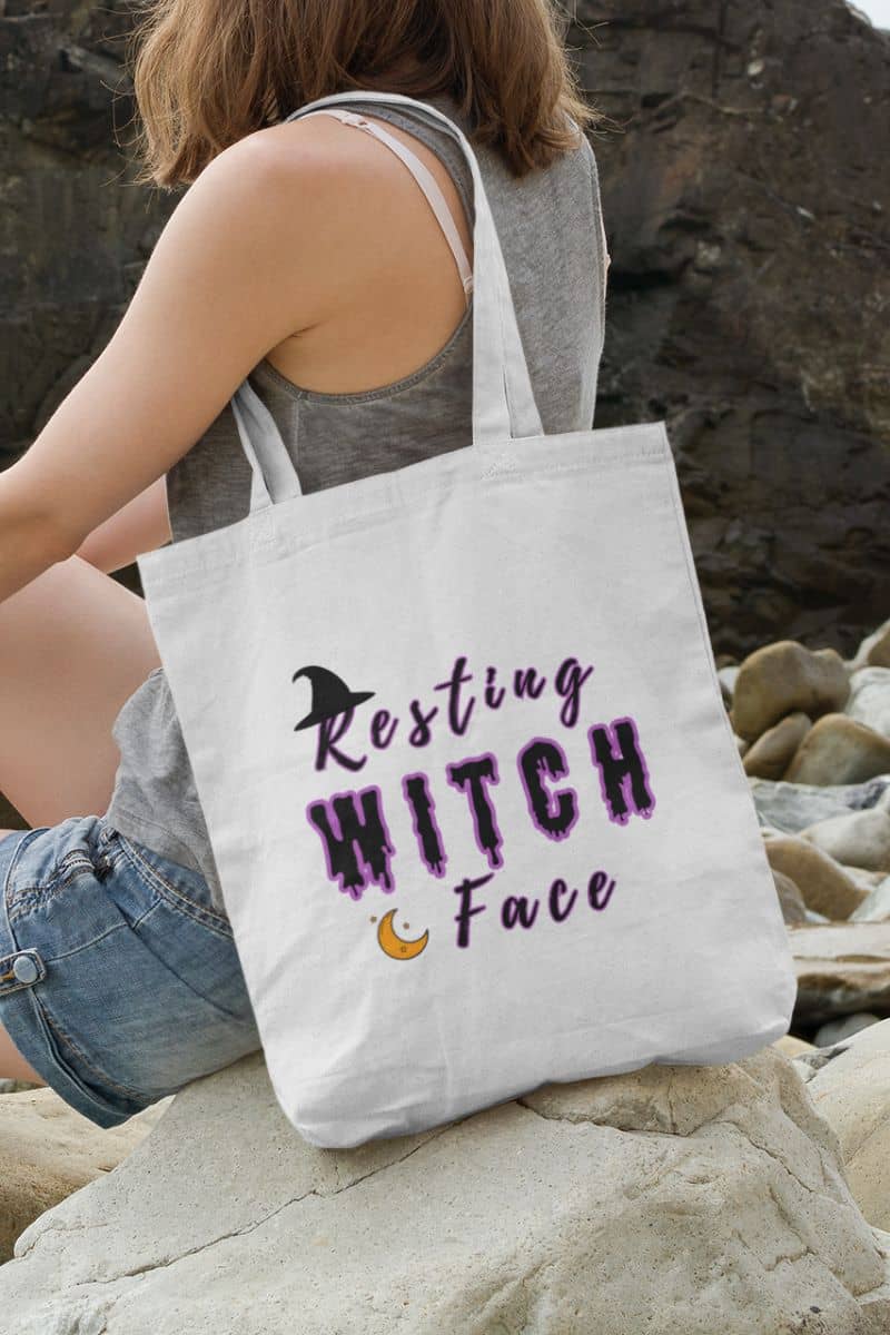 Funny Halloween bag with a person holding a tote bag with 'Resting Witch Face' text on a rocky surface
