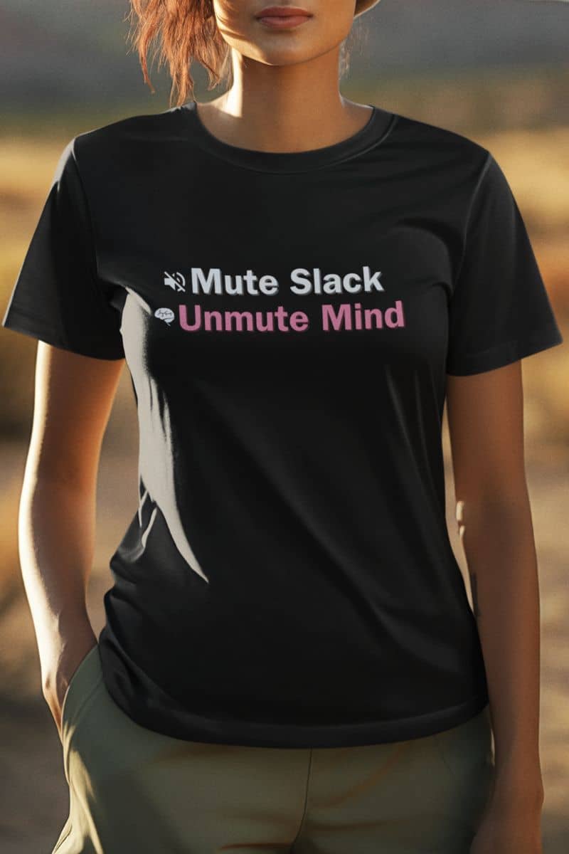 Funny burnout recovery tee with a person wearing a black t-shirt with text 'Mute Slack Unmute Mind' against a blurred natural background