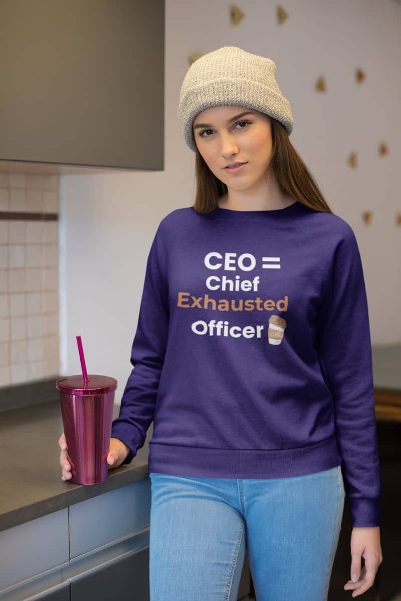 Funny business sweatshirt with a person wearing a purple sweatshirt with text 'CEO = Chief Exhausted Officer' in a kitchen setting