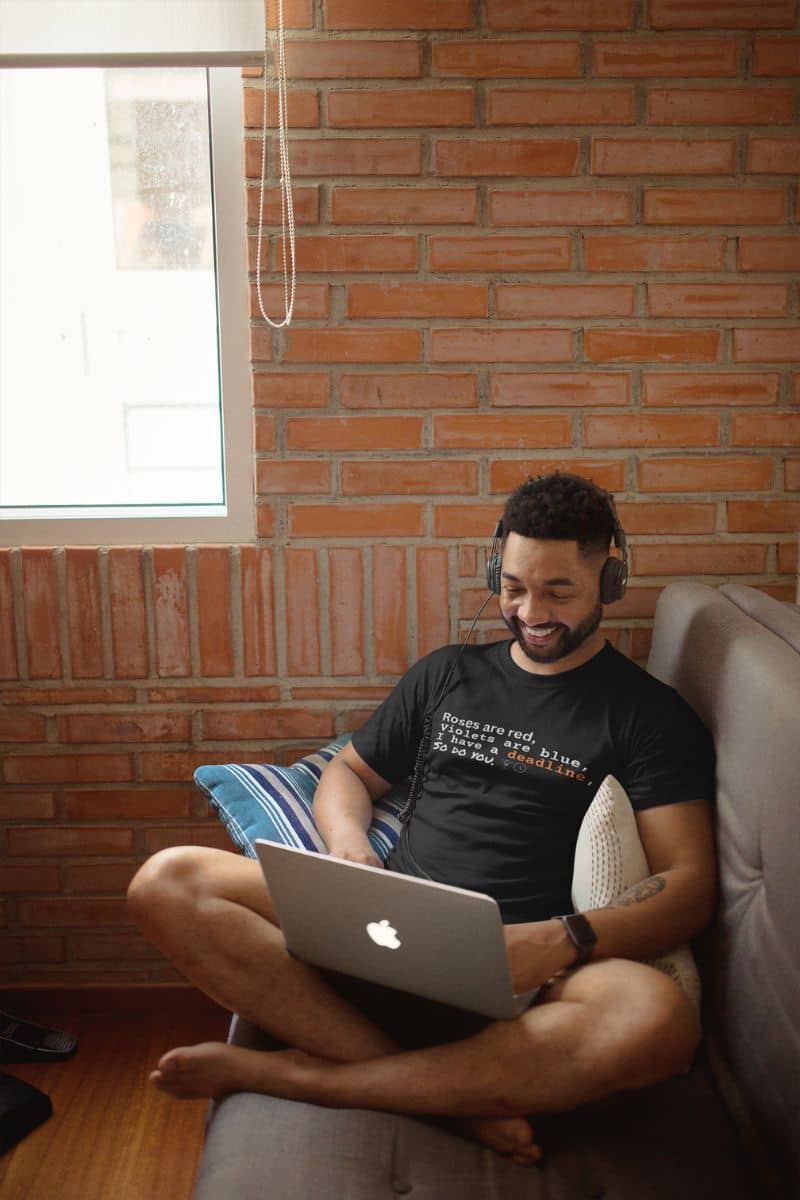 Funny deadline t-shirt with a guy sitting in a corner of the room with a laptop and headphones