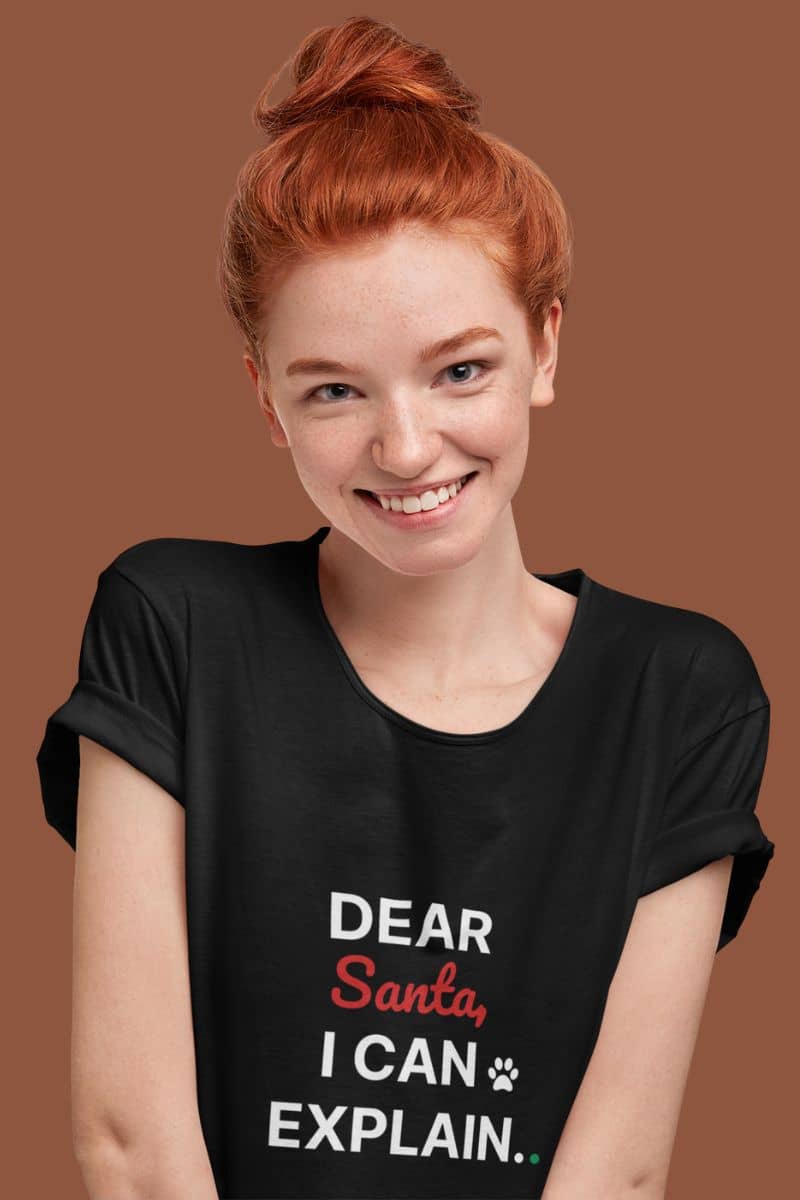 Funny holiday shirt with a person wearing a black t-shirt with 'Dear Santa, I can explain.' text on a brown background