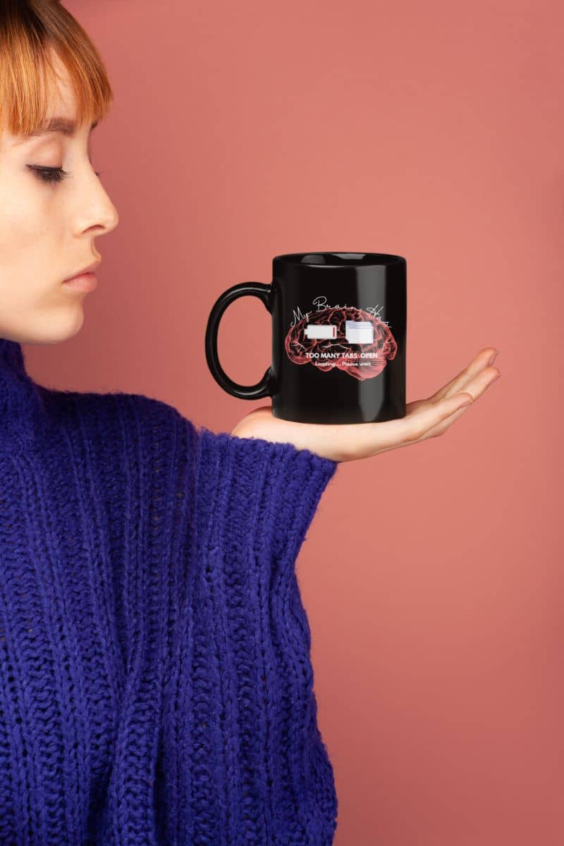 Funny mental overload coffee mug with a girl holding a cup in her hand and looking at it