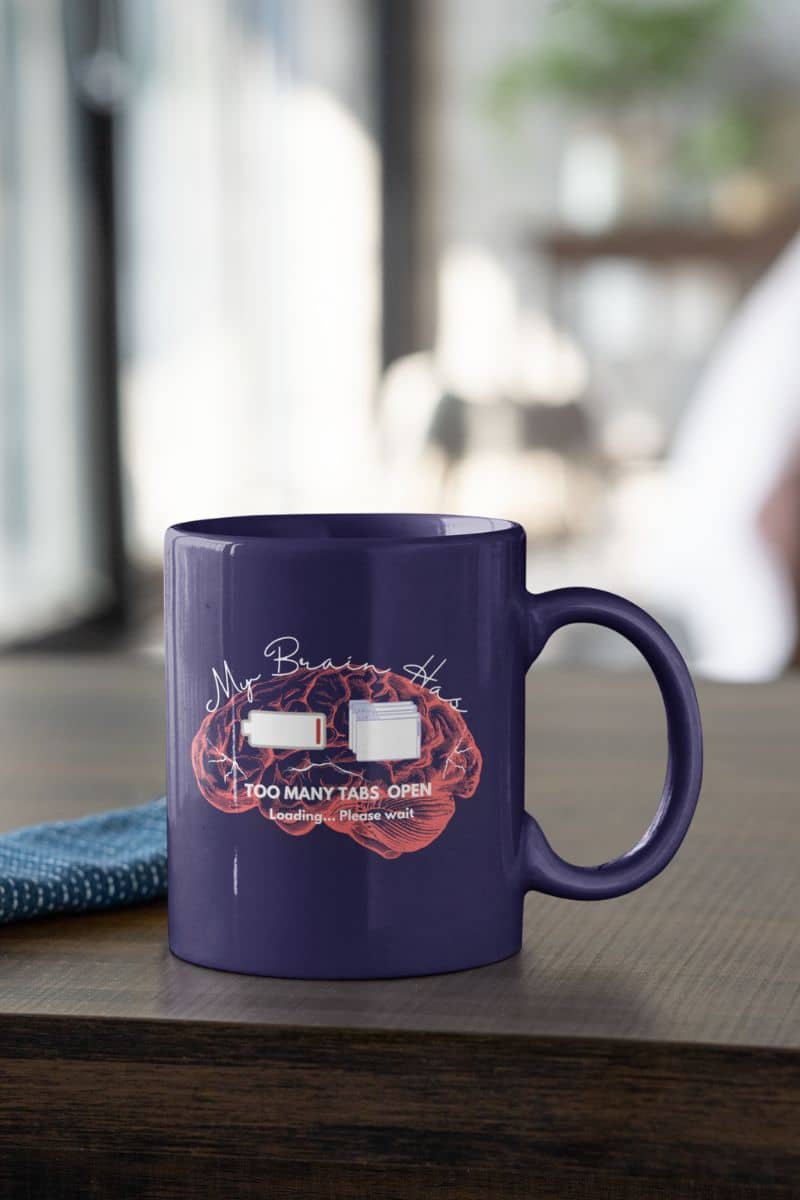Funny mental overload coffee mug with a cup of coffee on the table