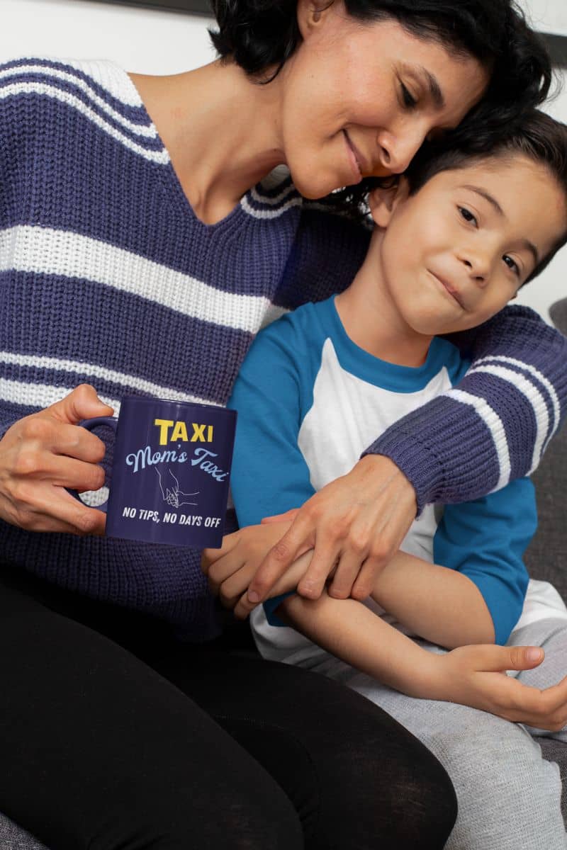 Funny mom's taxi coffee mug with a mother hugging her son while still holding a cup of coffee