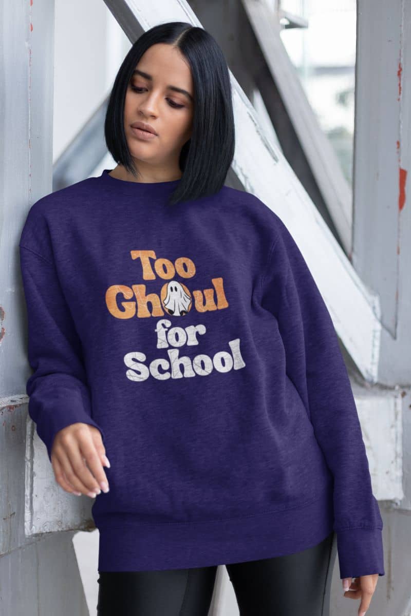 Ghost Halloween outfit with a person wearing a purple sweatshirt with 'Too Ghoul for School' text, standing against a white wall.