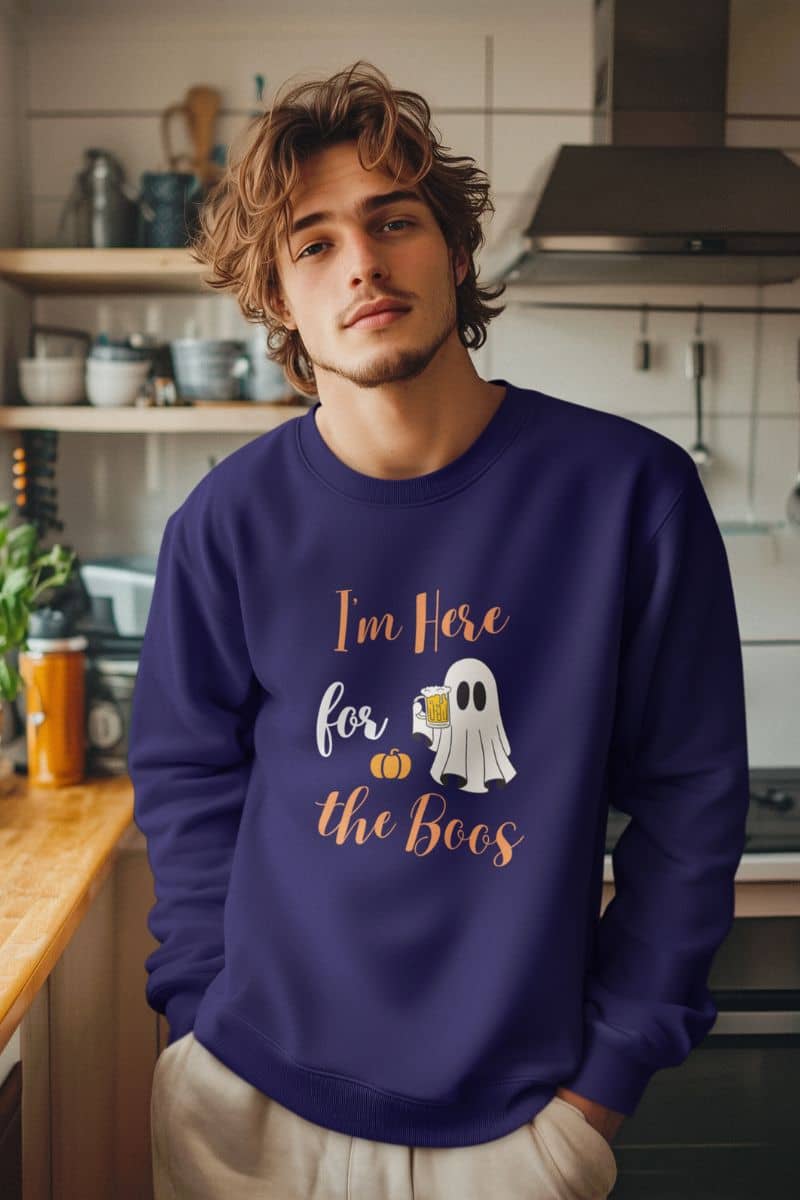 Ghost drinking sweatshirt with a man wearing a purple sweatshirt with text 'I’m Here for the Boos' in a kitchen