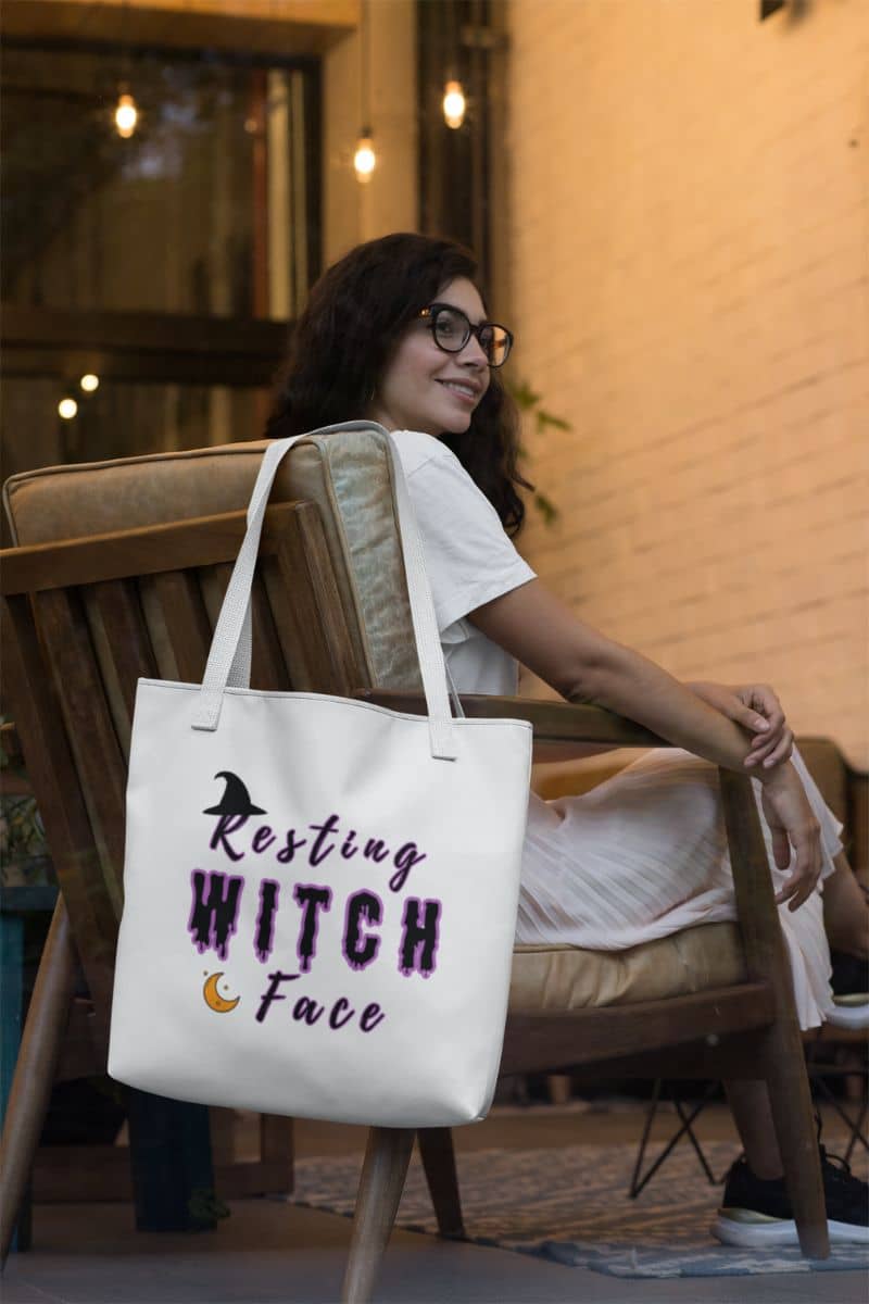 Halloween witch tote bag with a woman sitting on a chair with a tote bag featuring 'Resting Witch Face' text