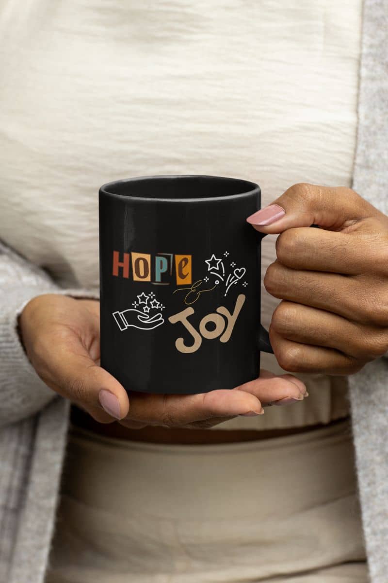 Hope and Joy Mug with a woman holding a cup of coffee in her hand