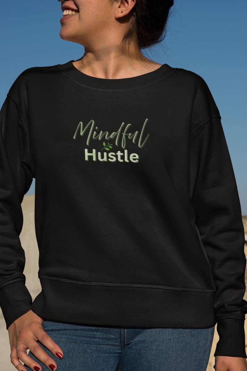 Inspirational quote sweatshirt with a person wearing a black sweatshirt with 'Mindful Hustle' text against a blue sky.