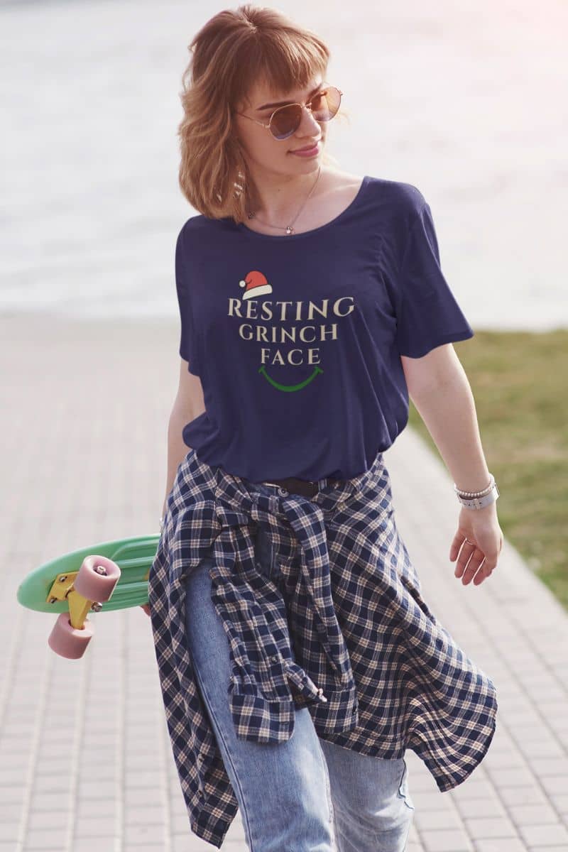 Introvert Christmas tee wiyh a person wearing a 'Resting Grinch Face' t-shirt with a skateboard in an outdoor setting