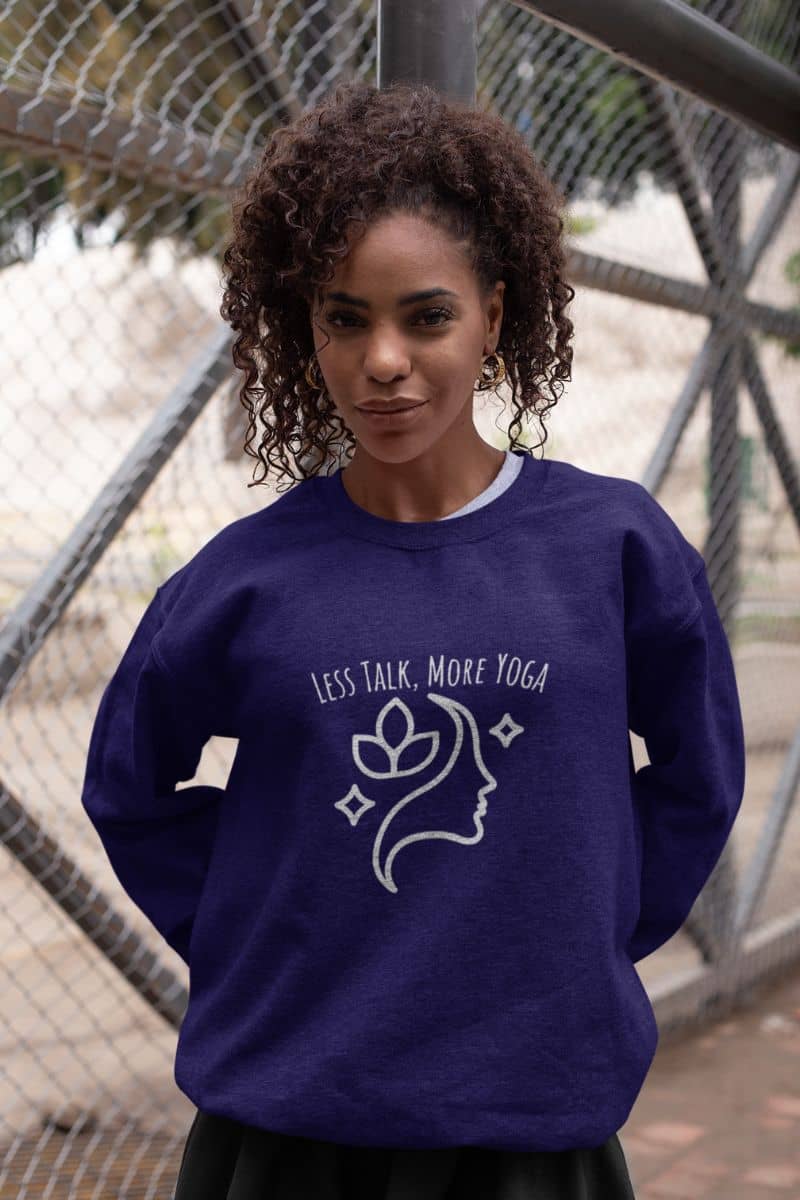 Less talk, more yoga sweatshirt with a curly-haired girl posing in front of the sports area fence