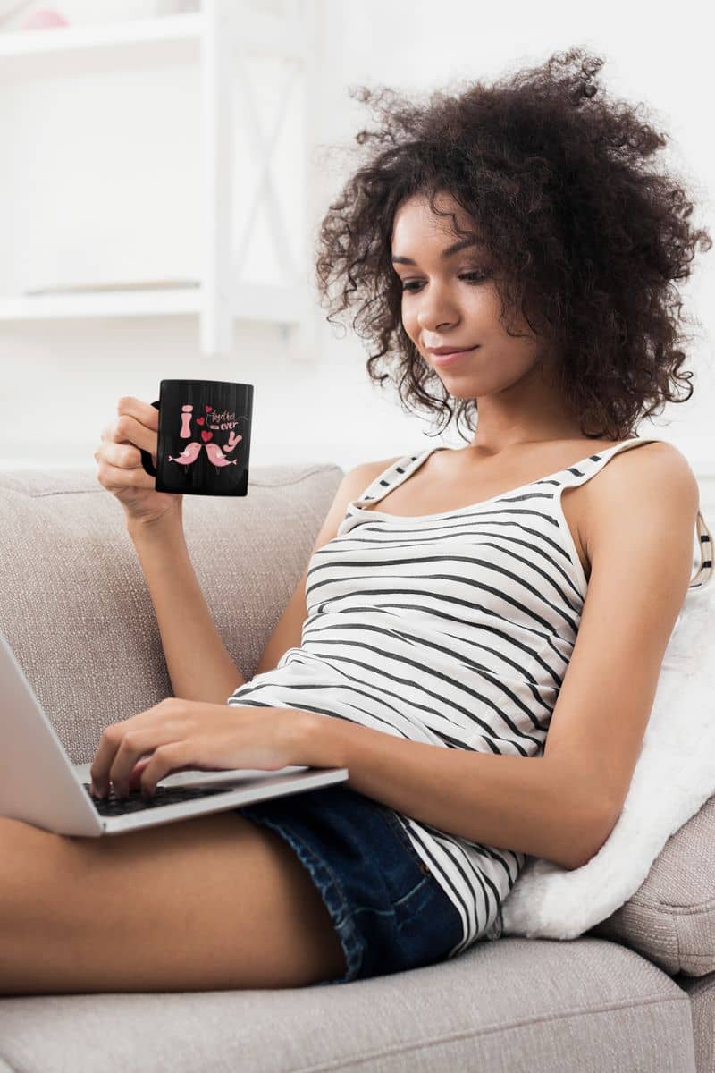 Love birds forever mug with a curly haired girl sitting working on a laptop on the sofa at home