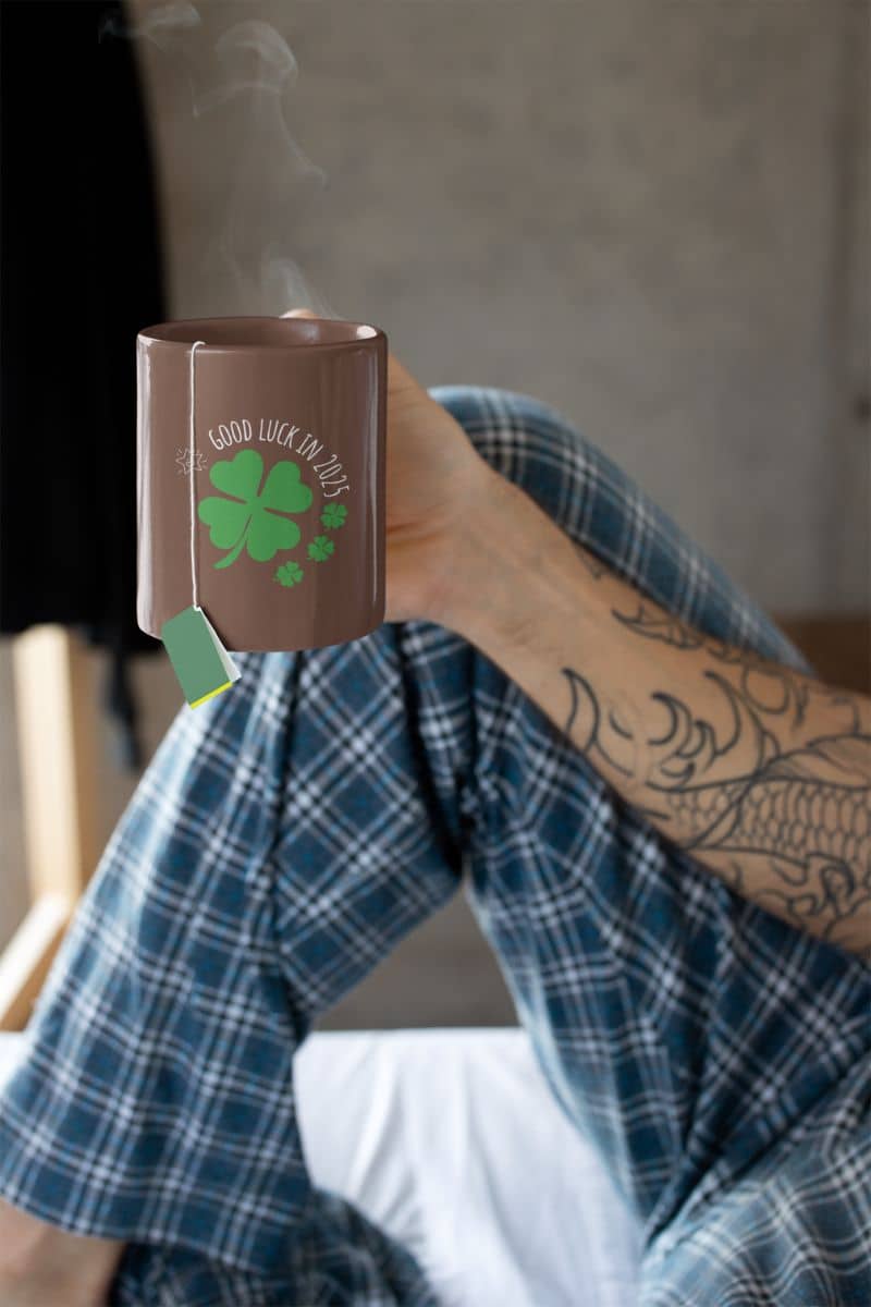 Lucky Charm 11 oz Mug with a guy wearing pajamas and holding a cup of tea on the bed