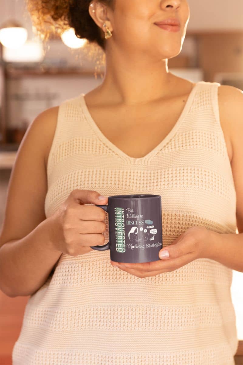 Marketing fuel mug with a woman holding a cup of coffee to her chest and looking in one direction in the kitchen