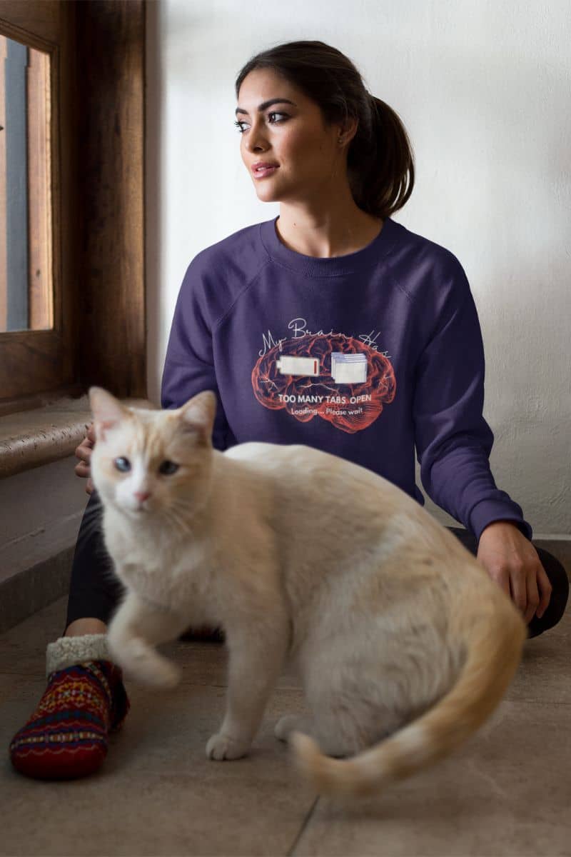 Mental overload sweatshirt with a young girl sitting on the wooden floor with her cat