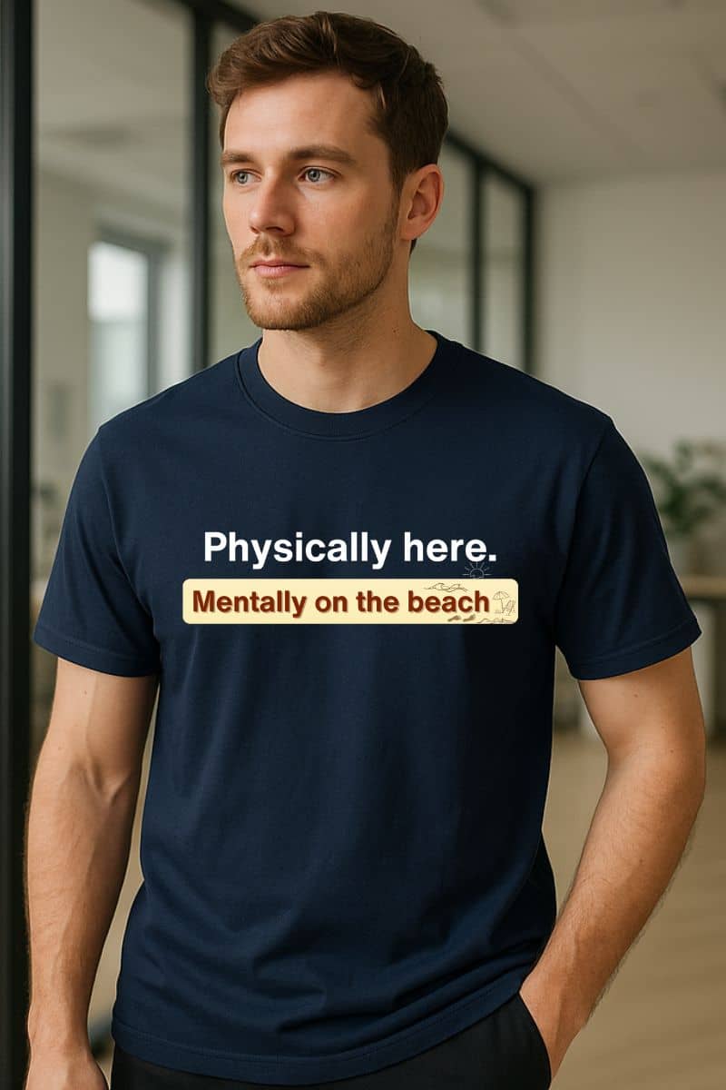 Mentally on the beach t-shirt with a man wearing a navy blue t-shirt with text 'Physically here. Mentally on the beach.'