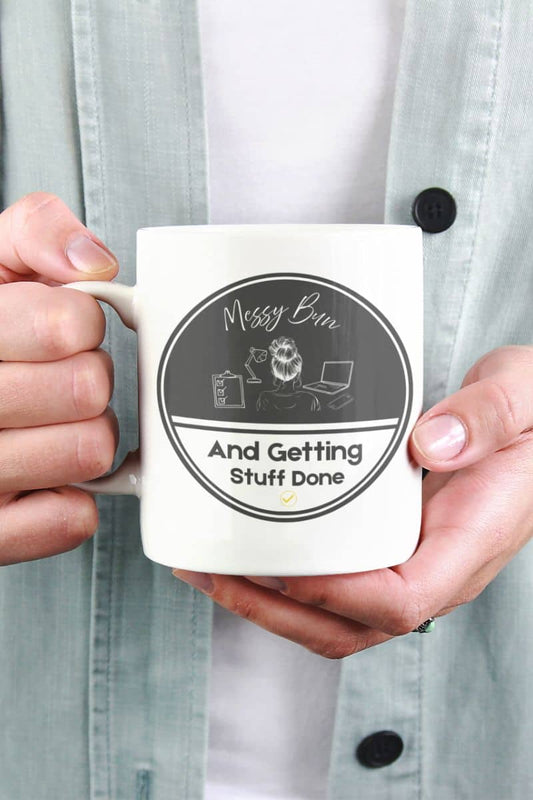 Messy bun coffee mug with a person holding a coffee cup in front of his chest with both hands