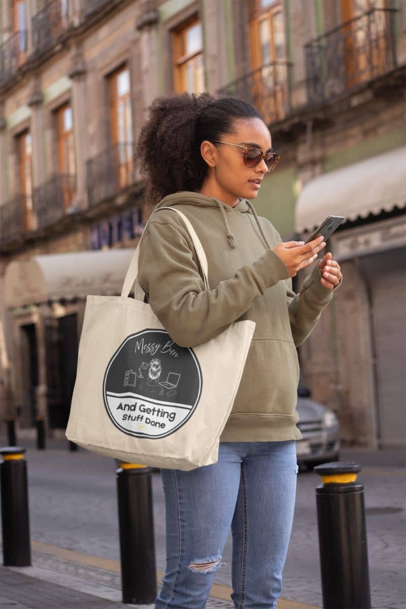 Messy bun tote bag with girl reading text message while walking down the street with big tote bag
