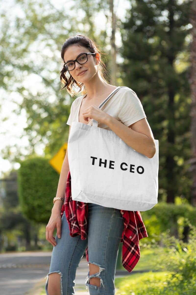 Minimalist canvas tote bag with a woman holding a tote bag with 'THE CEO' text outdoors