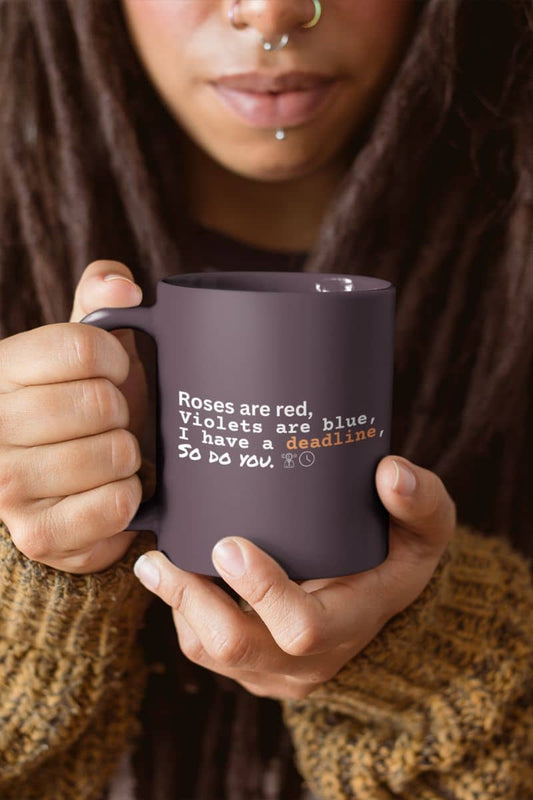Motivational deadline mug with a girl with piercings in her nose and mouth holding a cup in front of her chest