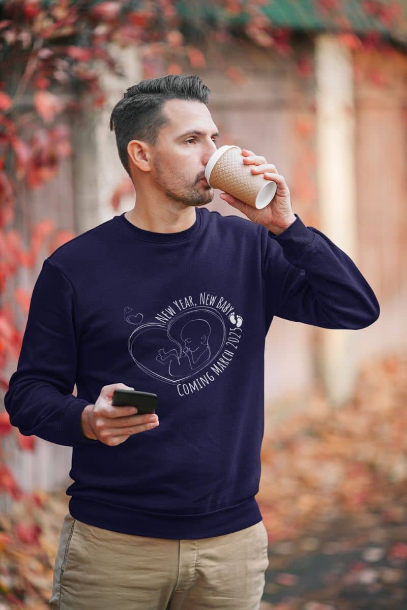 New year, new baby sweatshirt with a man drinking coffee while holding a phone in his other hand