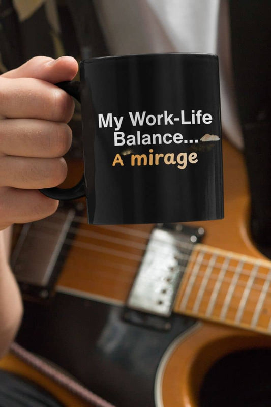 Office humor coffee mug with a person holding a black mug with text in front of an acoustic guitar
