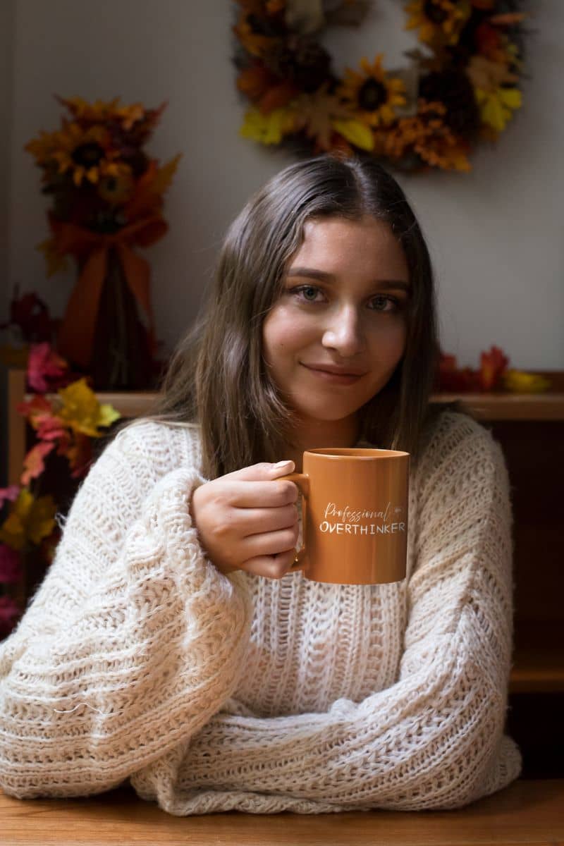 Overthinker mug with girl holding cup of coffee sitting in flower shop
