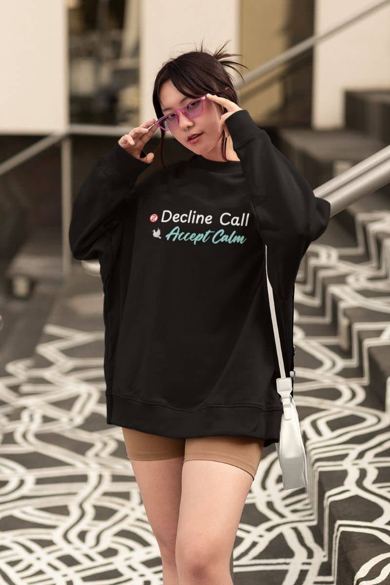 Positive mental health sweater with a person wearing a black sweatshirt with text 'Decline Call Accept Calm', standing on a patterned floor.