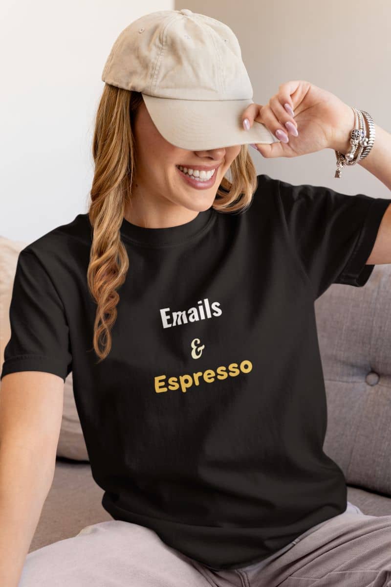 Productivity t-shirt with a woman wearing a black t-shirt with 'Emails & Espresso' text, sitting on a couch.