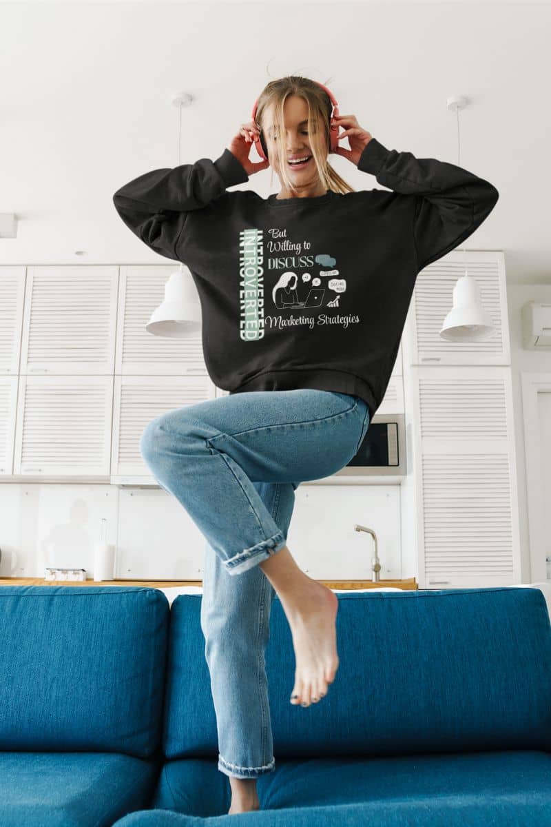 Quiet hustler sweatshirt with a girl jumping on the sofa while holding headphones on her head