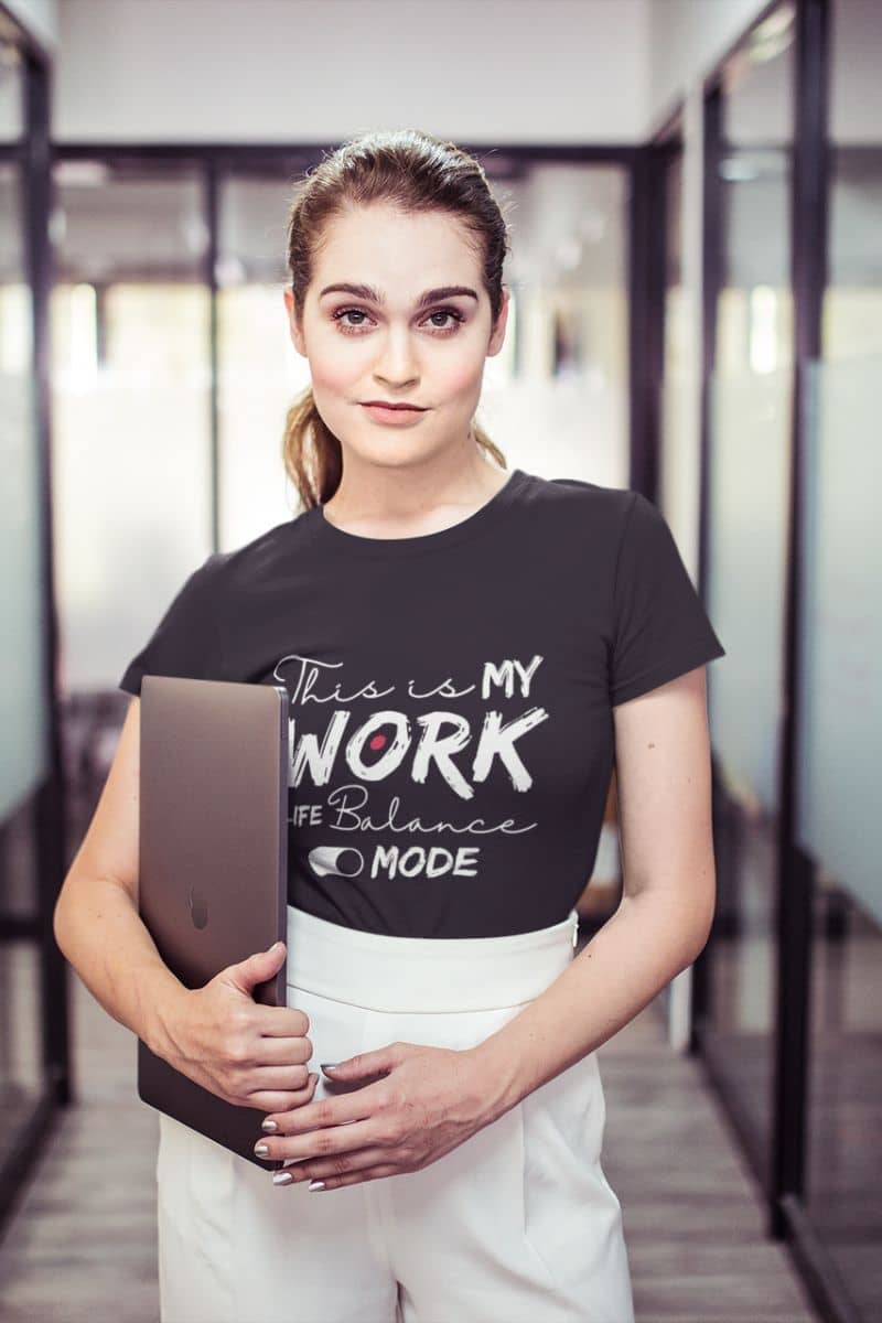 Relaxed work-life balance t-shirt with a woman posing with her laptop in the office hallway