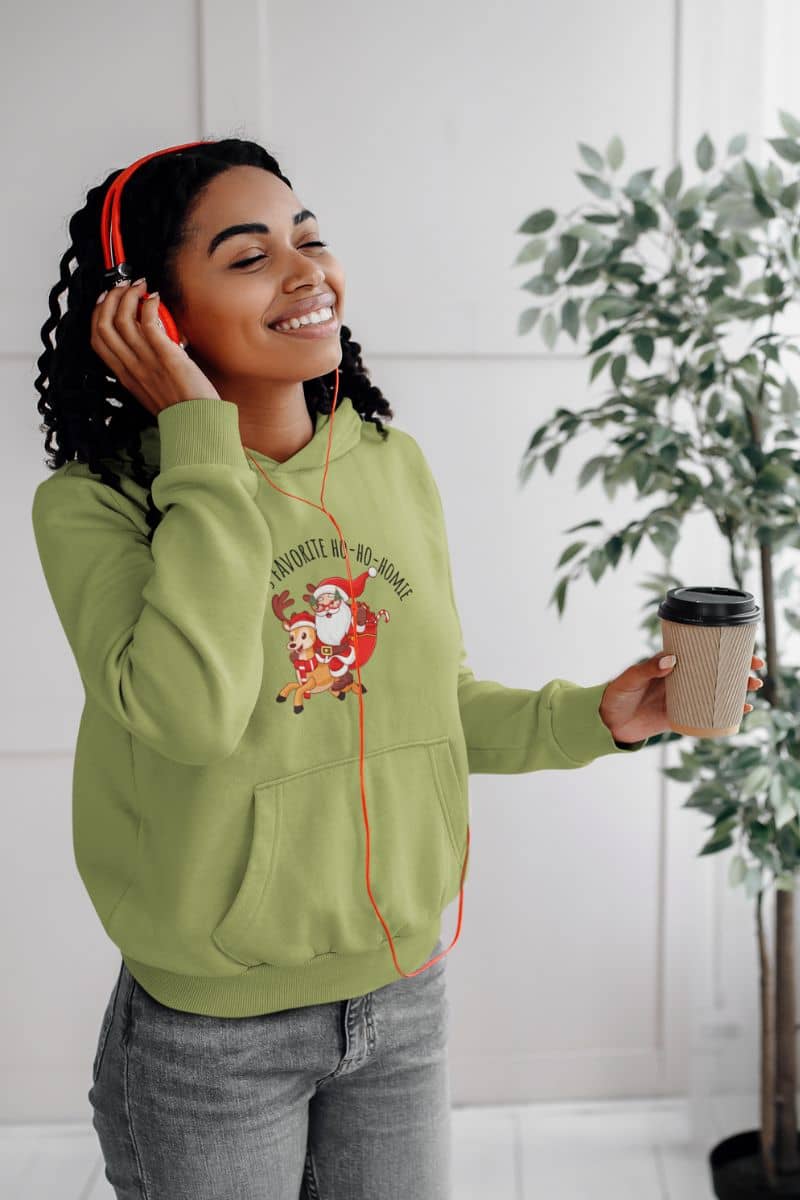 Cozy Christmas Hoodie with a girl wearing headphones swaying to the music while holding a cup of coffee