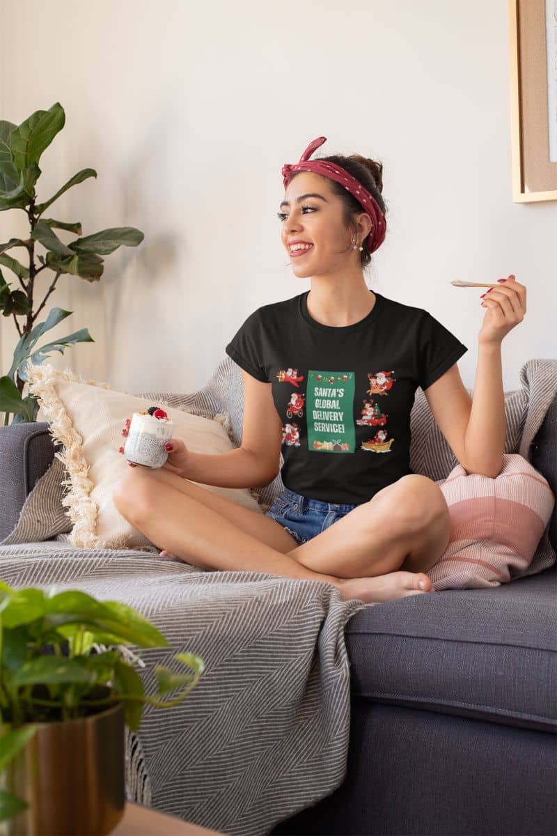 Santa's Global Delivery Service Festive Holiday T-Shir With a girl eating healthy food on the sofa