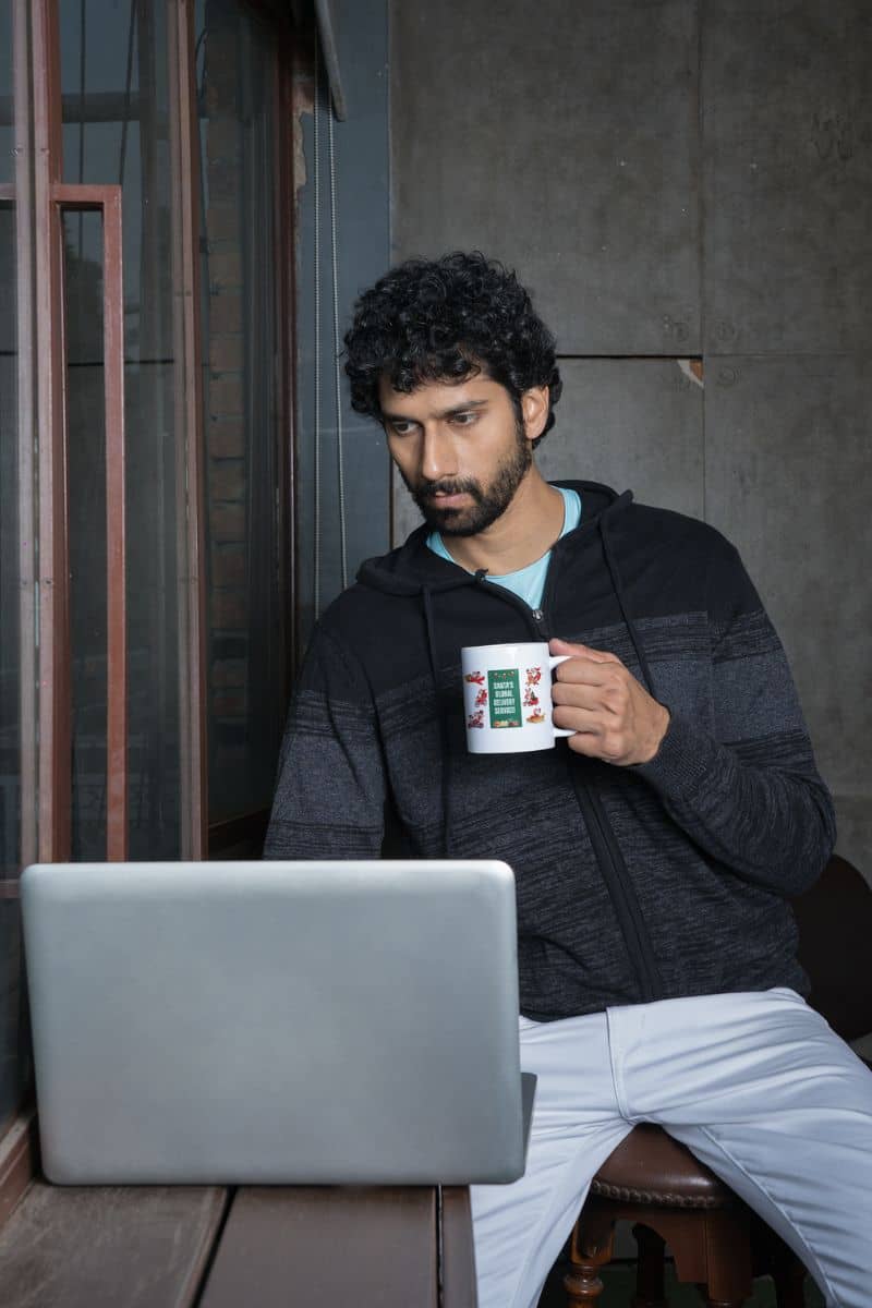 Santas Global Delivery Service Mug with a man working on a laptop