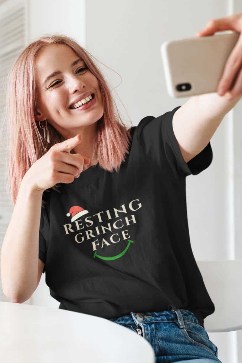 Sarcastic Holiday shirt with a person wearing a black t-shirt with 'Resting Grinch Face' text, taking a selfie.
