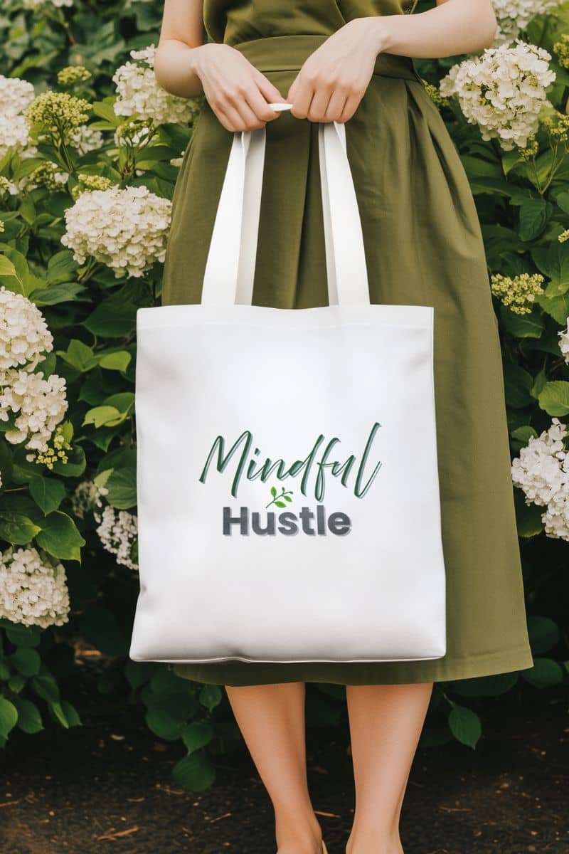 Self-love canvas tote with a person holding a white tote bag with 'Mindful Hustle' text against a floral background